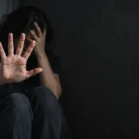 Woman shielding her face and holding an open hand toward the camera